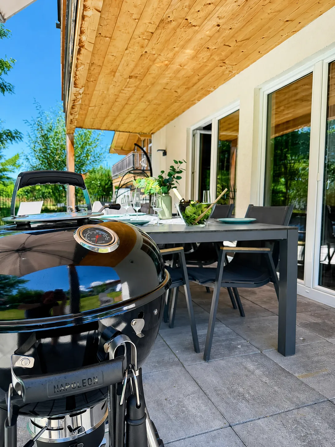 Terrasse mit Kugelgrill und gedecktem Esstisch